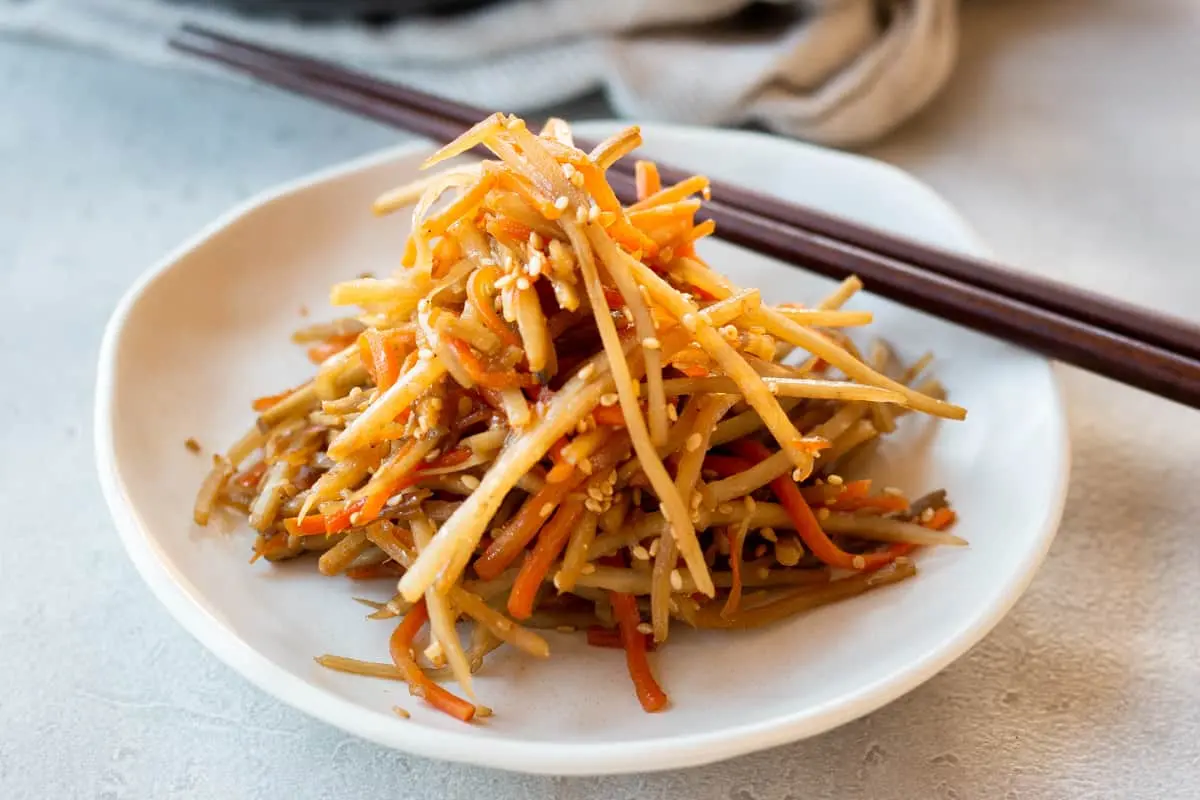 Kinpira Gobo thành phẩm màu nâu đỏ bóng rắc mè trắng ăn kèm cơm trắng nóng
